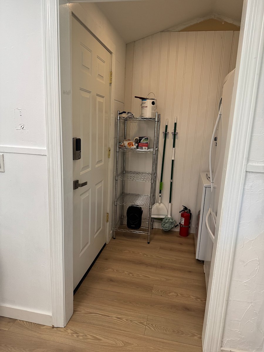 Laundry room just off of kitchen with secondary door to yard. BBQ tools, broom, mop, dustpan, iron and board