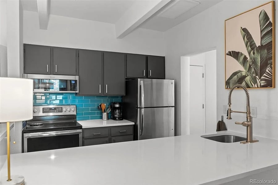 Renovated, open kitchen with full refrigerator, electric stove, slim profile microwave, and dishwasher.