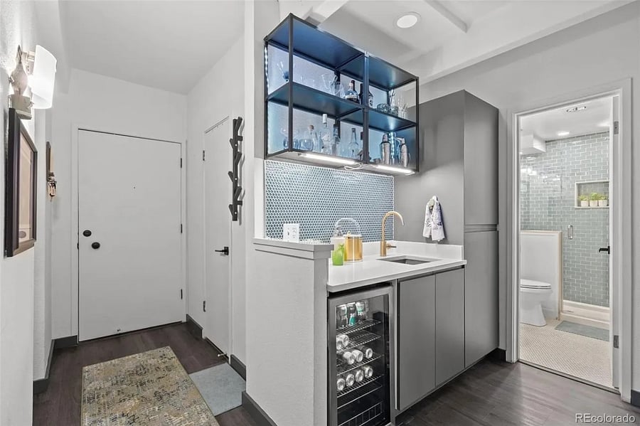 Entrance from interior hallway leads to wet bar with sink, shelving, and below counter beverage chiller.
