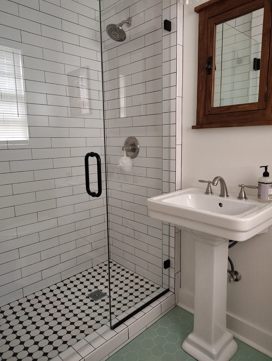 Tile shower with glass door. Built -in medicine cabinet above pedestal sink.