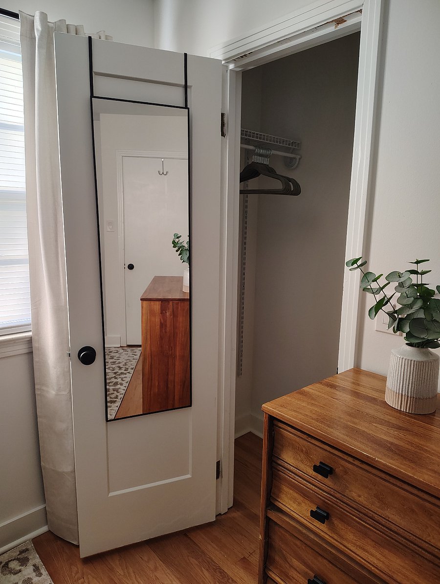Closet with full-length mirror and hangers.