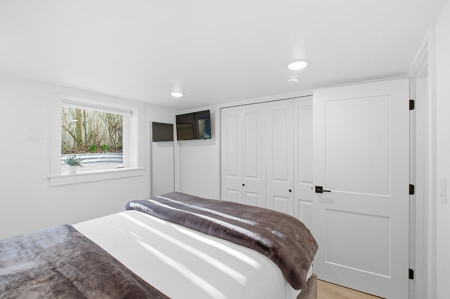 South bedroom with hanging and dresser storage and large window. 