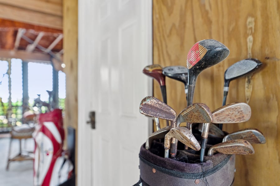 Older set of golf clubs located under the house for guest use