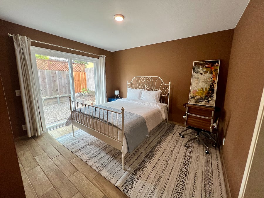 Comfortable second bedroom with a queen bed and movable desk. The sliding door provides access to the backyard.