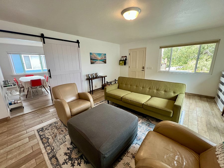 The living room with a sofa, two arm chairs, and additional chairs.