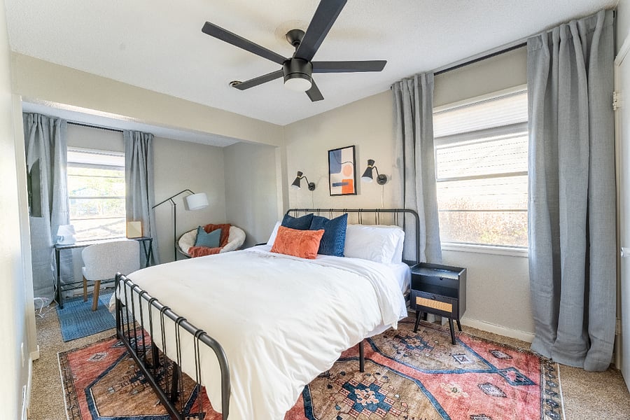 Large, bright bedroom with king bed, convenient bed sconces for reading, smart tv and dedicated desk overlooking large backyard