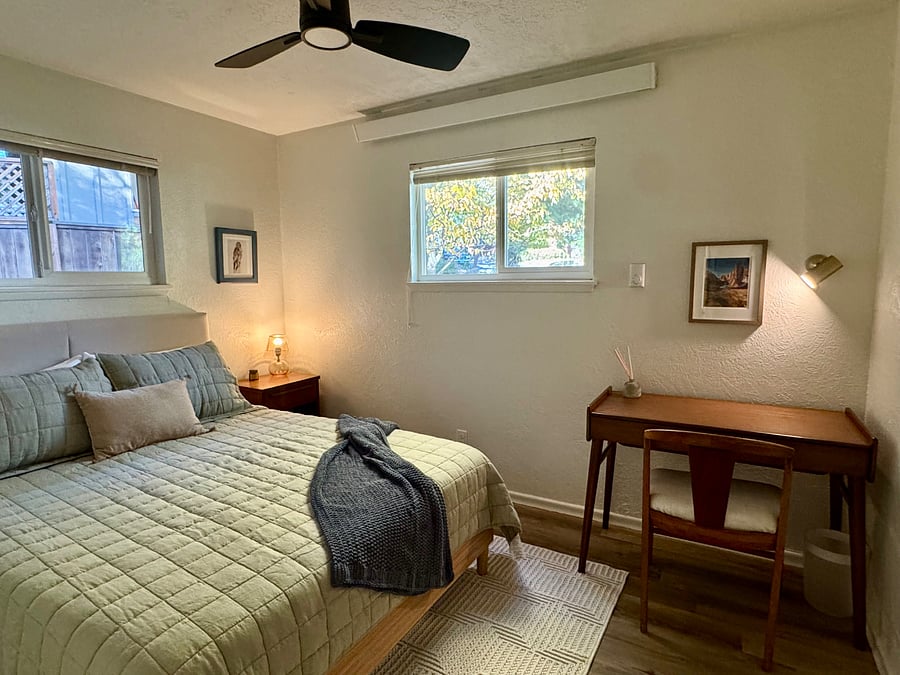 Back bedroom with new bedframe, mattress, and luxury bedding. Workspace in the corner.