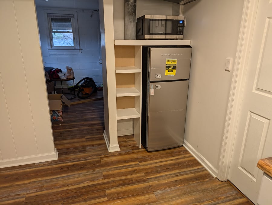 kitchenette with fridge and door facing living room