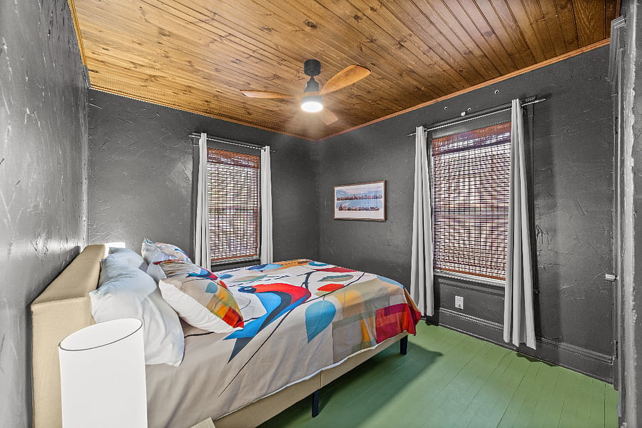 Blackout curtains over whicker blinds with a pine ceiling and painted floor