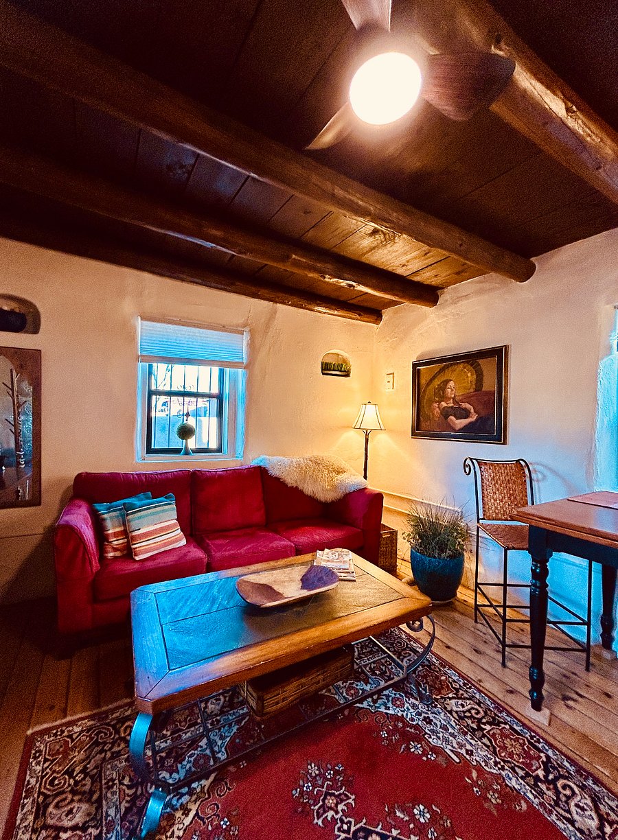 Living room and dining area. Large space with hand crafted tin door for entry. Gas heater for winter, large television for streaming, oversized and comfy couch. Vigas and original plank floors. Wonderful sunlight exposure in early mornings and afternoons.