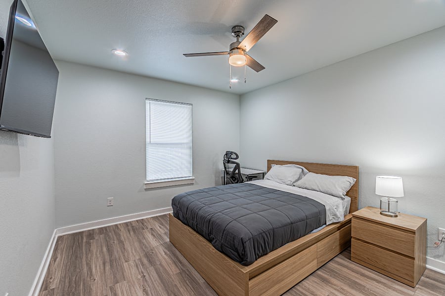Master Bedroom. Full size bed with 4 drawers at the bottom. Nightstand, lamp, TV, Desk and Chair. 