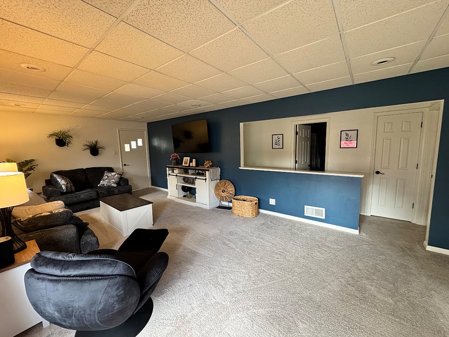 Living Room with Couch, Love Seat, Chair, two end tables, coffee table and 65 inch smart TV. Bathroom is off the living room.