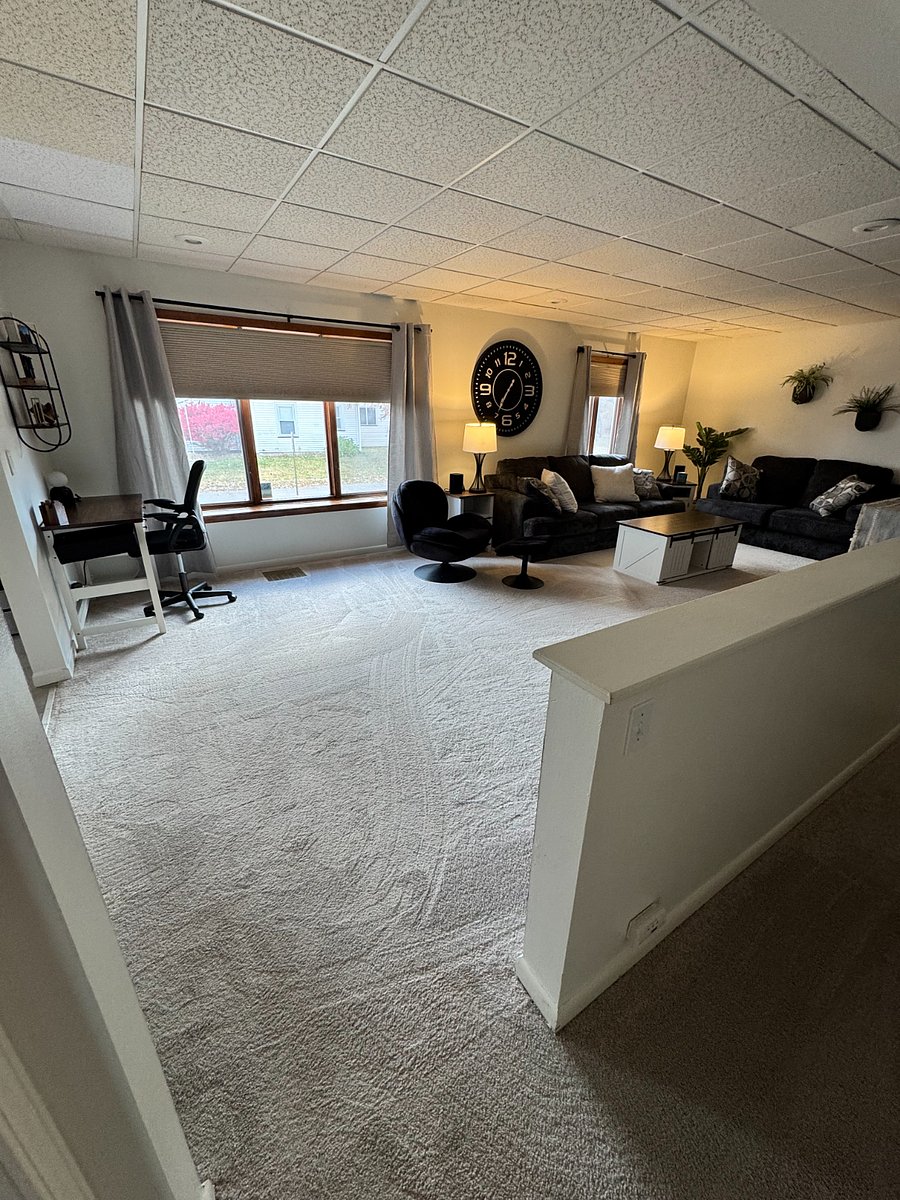 Living Room with Couch, Love Seat, Chair, two end tables, coffee table and 65 inch smart TV. Large window with natural light.