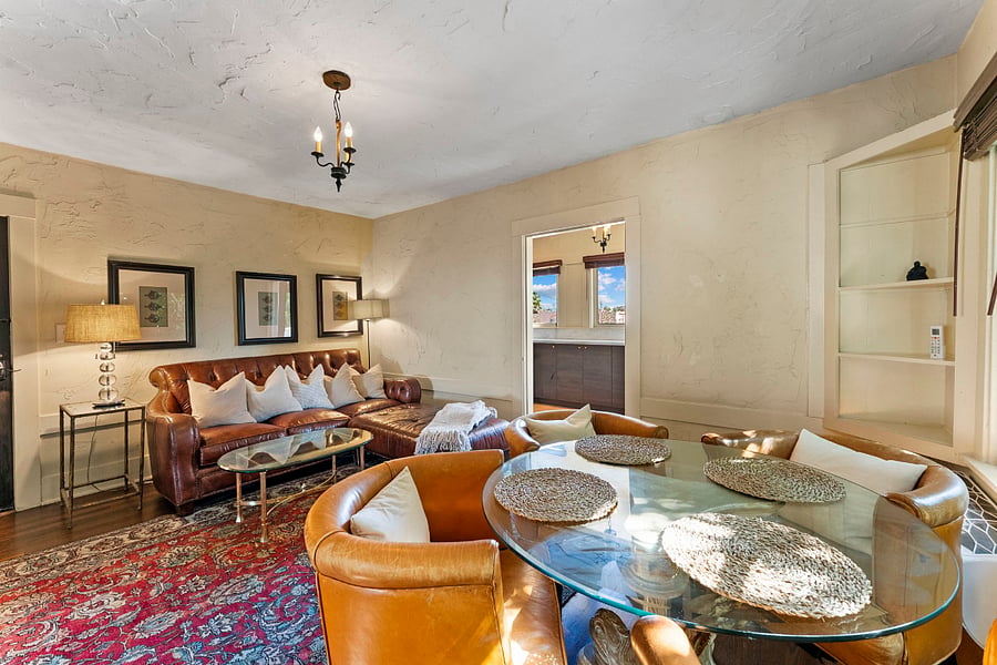 Comfy leather love seat sectional with cushy pillows and soft cable knit blanket. two side tables with lamps. Glass top coffee table. Glass top dining table with 4 chairs.