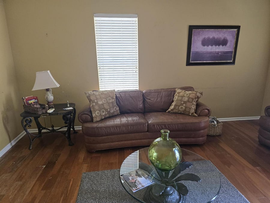 Enjoy a warm, inviting living room with plush leather seating, neutral tones, and charming dcor. A large window brings in plenty of light, making it the perfect space to unwind after a long shift.