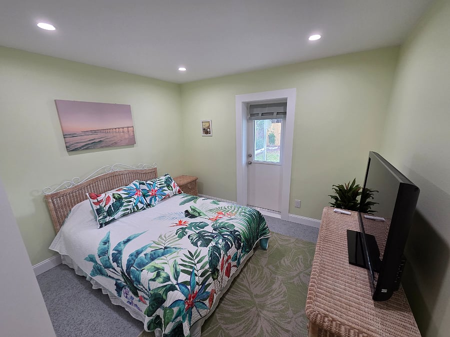 guest bedroom with large closet, queen bed, large dresser and tv. 
