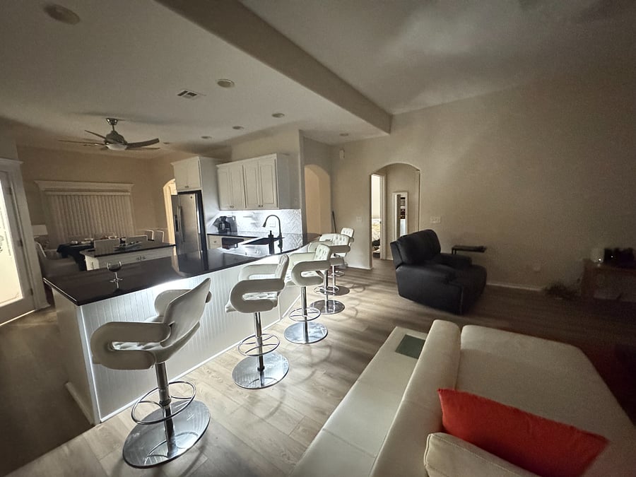 Open kitchen with black granite counters, white cabinets, and full cookware for home dining.
