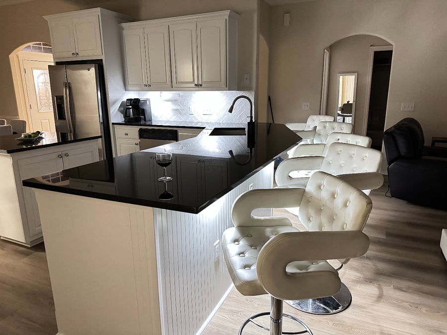 Open kitchen with black granite counters, white cabinets, and full cookware for home dining.