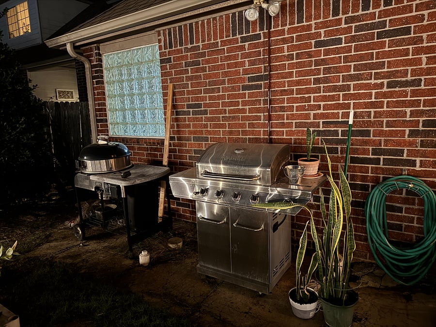 Spacious backyard with gas and charcoal grills, next to sunfoof dining area.