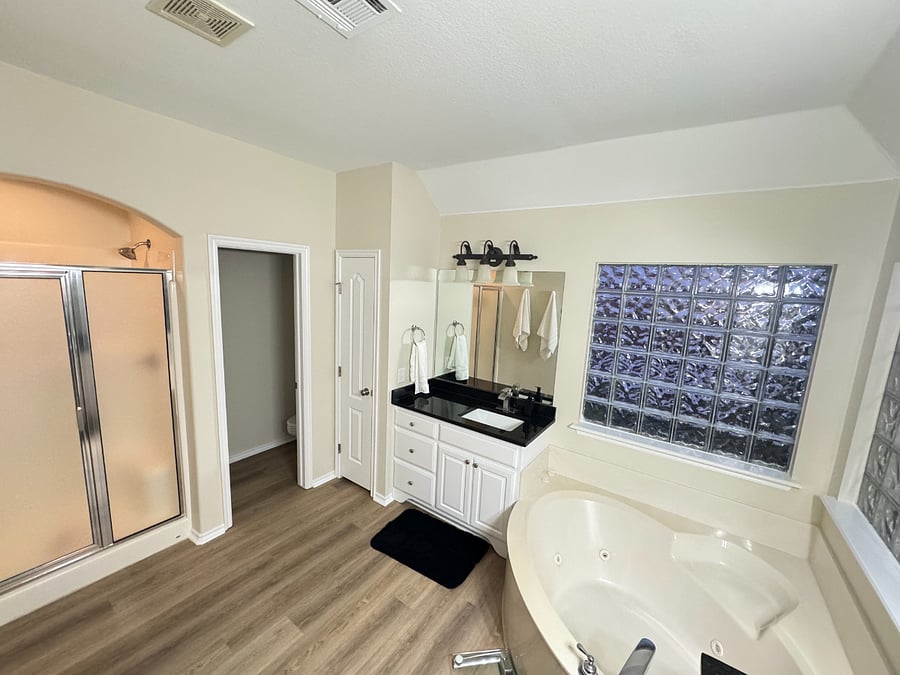 Spacious master bath with dual sinks, private shower, relaxing bathtub, and natural light for a bright, comfortable feel.