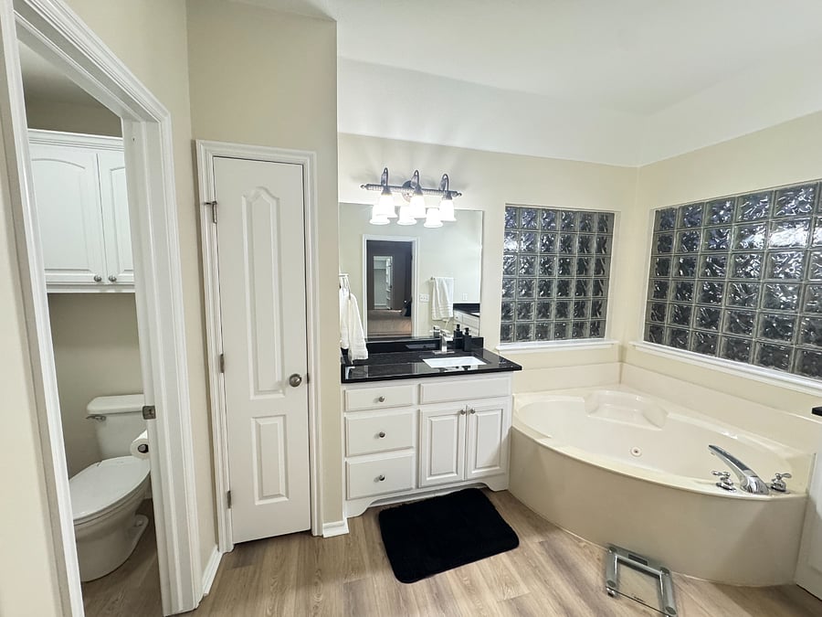Spacious master bath with dual sinks, private shower, relaxing bathtub, and natural light for a bright, comfortable feel.