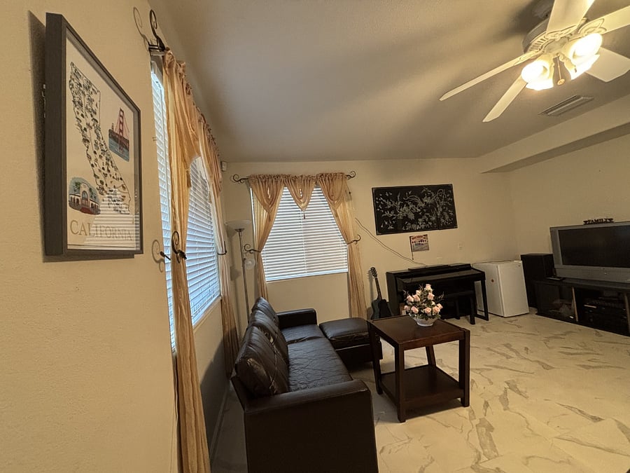 Living room with a brand-new sofa, piano, and TV.