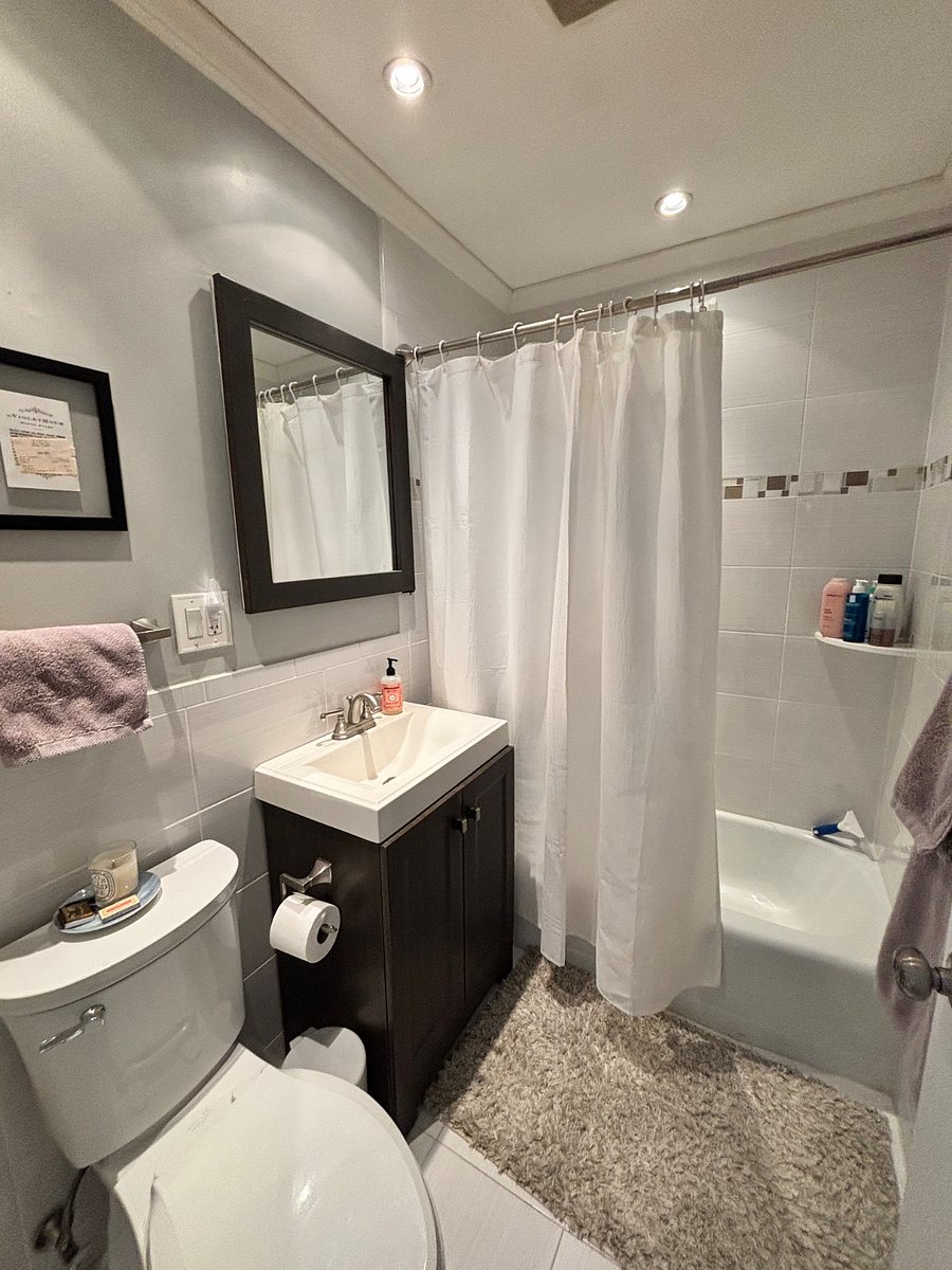 Modern and sleek bathroom with tub/shower and storage (behind mirror, and in cabinet)