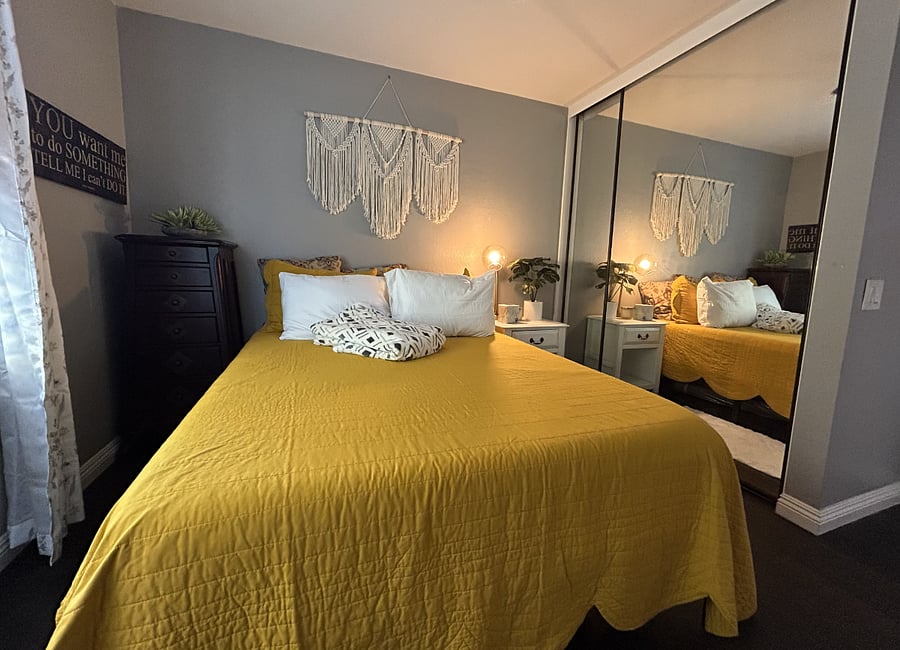 Secondary Bedroom. Comes with a separate bathroom, a large closet, two dressers, a bedside table, and a view of the outdoor pool. The mirrored wall is the closet, which comes with a high storage rack, hangers, another medium dresser, and a winter comforter.