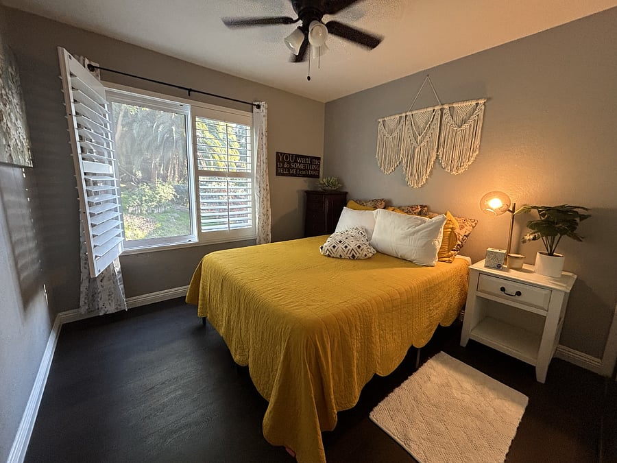 Secondary Bedroom. Comes with a separate bathroom, a large closet, two dressers, a bedside table, and a view of the outdoor pool. The mirrored wall is the closet, which comes with a high storage rack, hangers, another medium dresser, and a winter comforter.