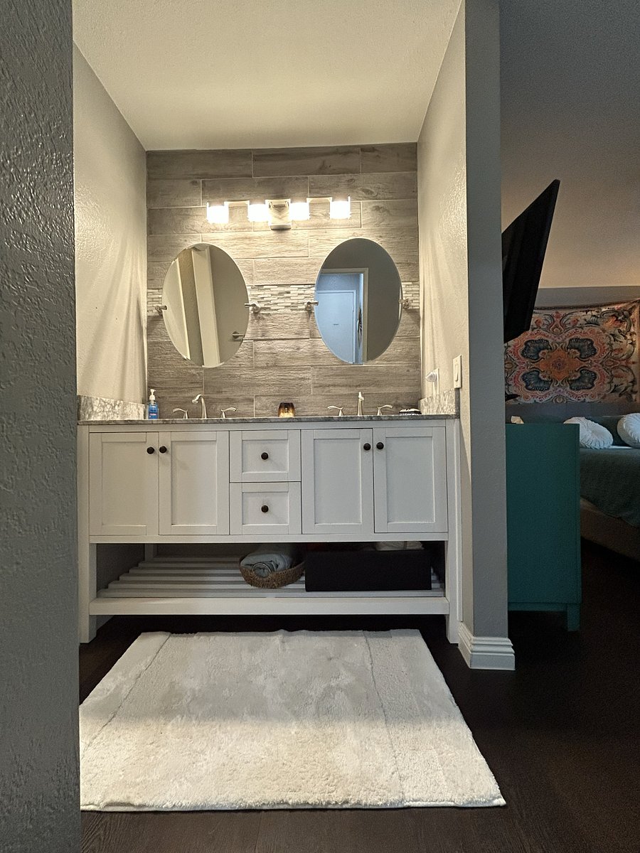 Primary/Master Bathroom features a double-sink vanity adjacent to a separate toilet. A privacy door can be drawn to separate the bedroom from the toilet. Lots of storage space in the vanity cabinets and the shelving below.
Features towel and wash-rag hanging hooks and some starter toiletries, soaps, and beauty care supplies.