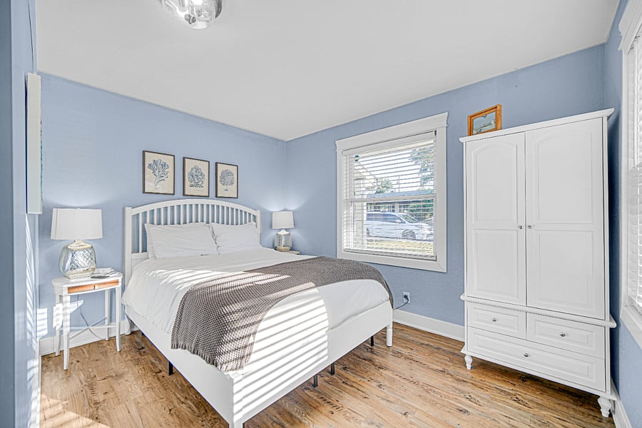 Relax in the primary bedroom featuring plush bedding, Smart TV, and calming coastal tones for a perfect night's rest.