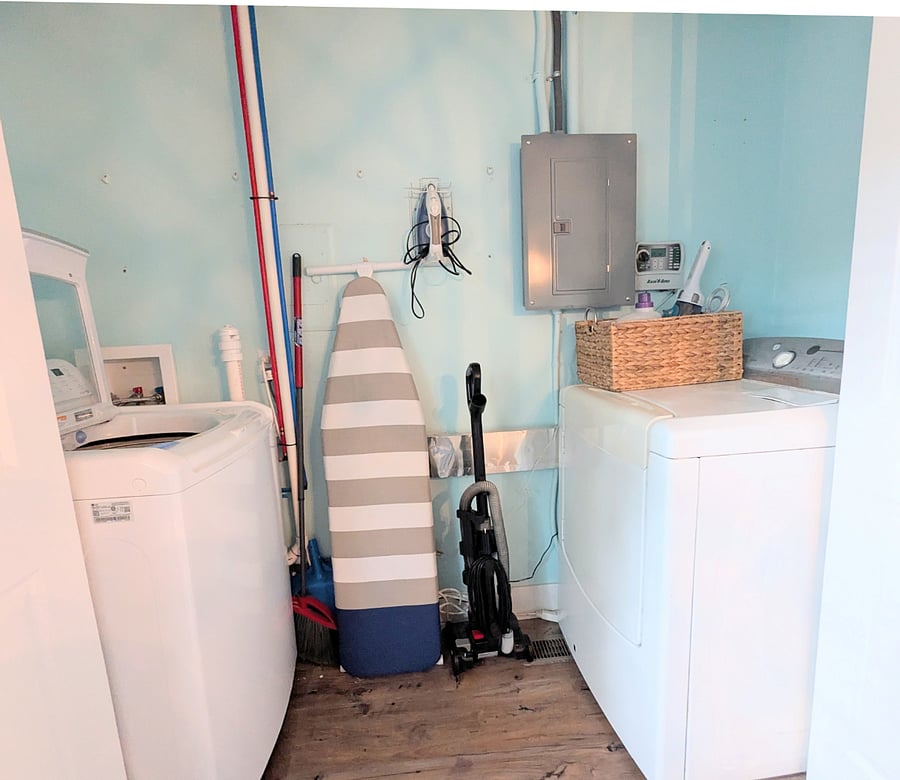 Fully equipped laundry room with washer, dryer, iron, ironing board, vacuum, and broom.