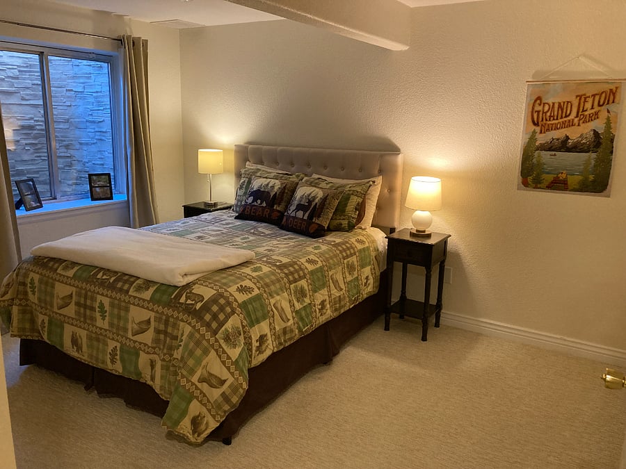 Basement suite features cozy mountain-themed bedroom.