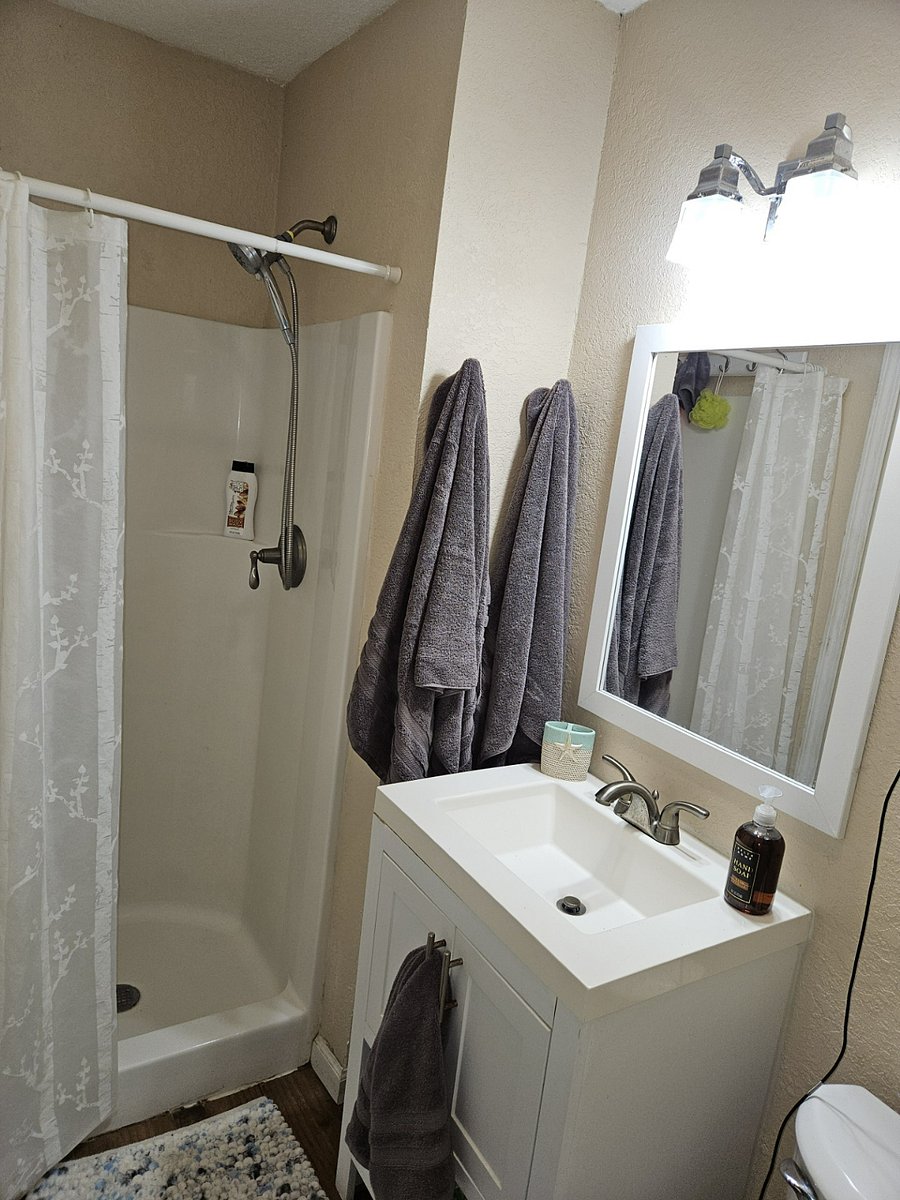 Bathroom with toilet, sink, shower, cabinet storage