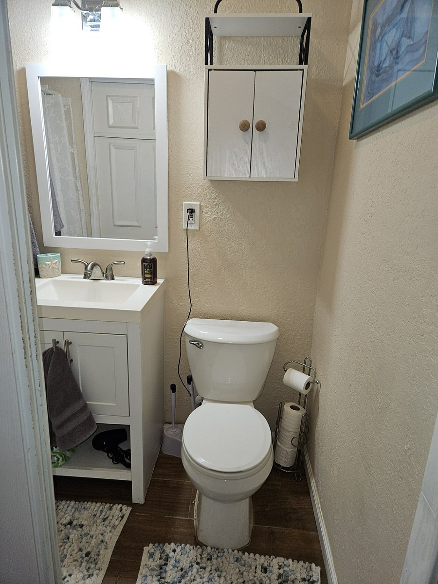 Bathroom with toilet, sink, shower, cabinet storage