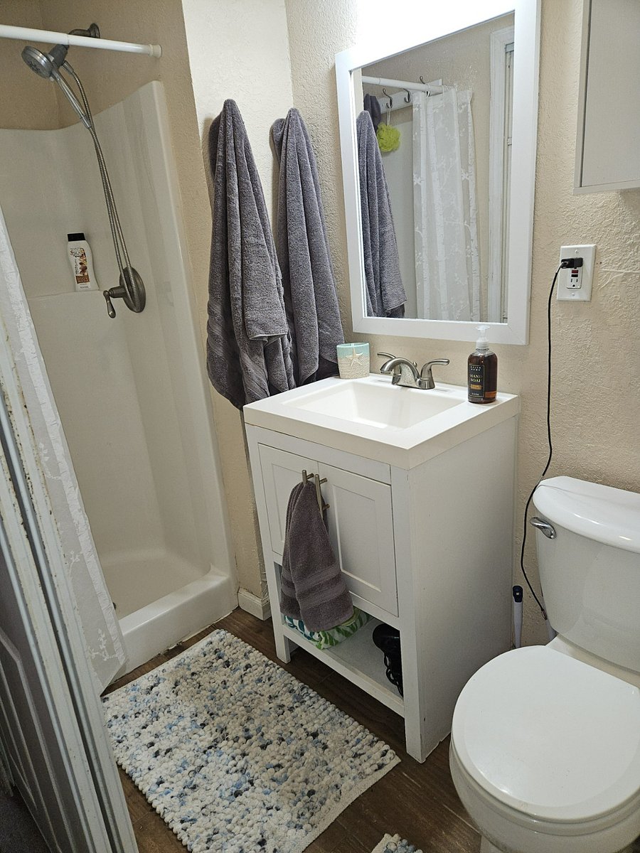 Bathroom with toilet, sink, shower, cabinet storage