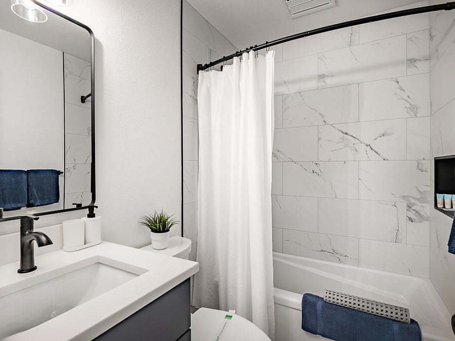 Modern bathroom with sleek marble accents and plush towels on main floor downstairs.