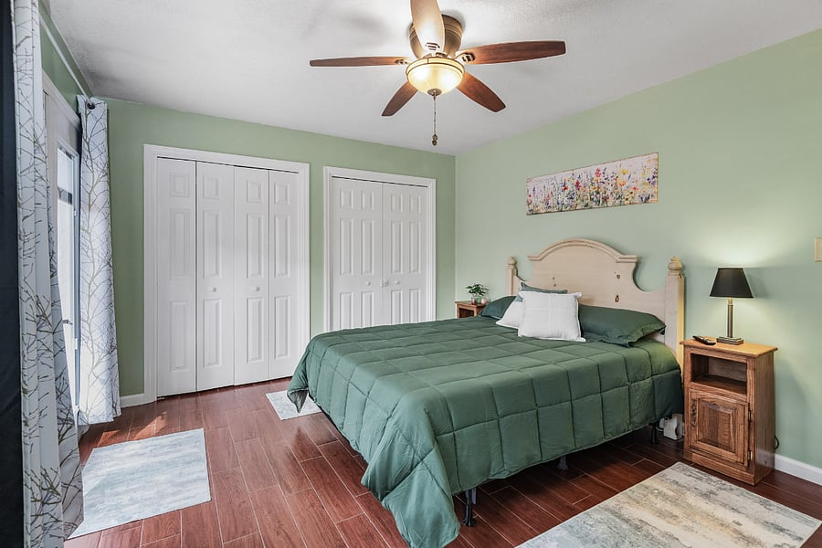 Primary suite features queen size bed, dresser, ample closet space full bathroom, and deck access.