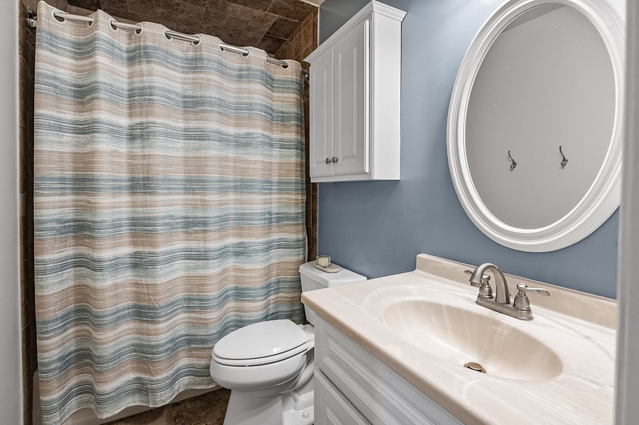 Guest bathroom features bathtub/shower, storage space, and exhaust.