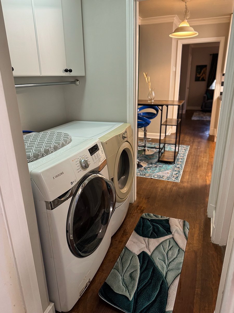 Laundry area features washing machine and clothes dryer, table-top ironing board and iron, with linens and supplies stocked in the cabinets above.