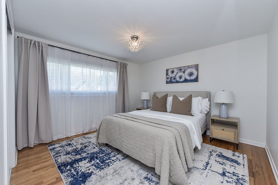 This serene bedroom is appointed with a memory foam mattress dressed in posh linens, complemented by coordinating nightstands with lamps and effective blackout blinds for a perfect night's rest.