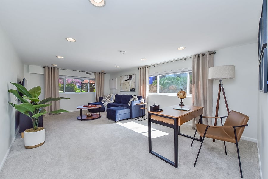 This brightly lit basement, comfortable living space, with board games, and a cozy desk. 