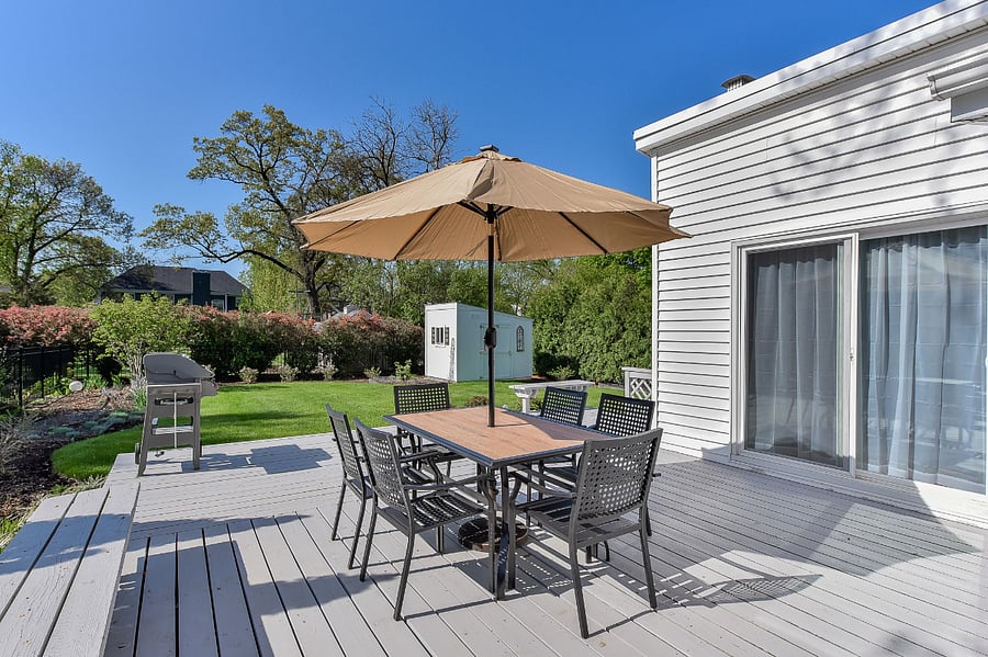 Spacious outdoor area, features a dining set with an umbrella and propane gill.  