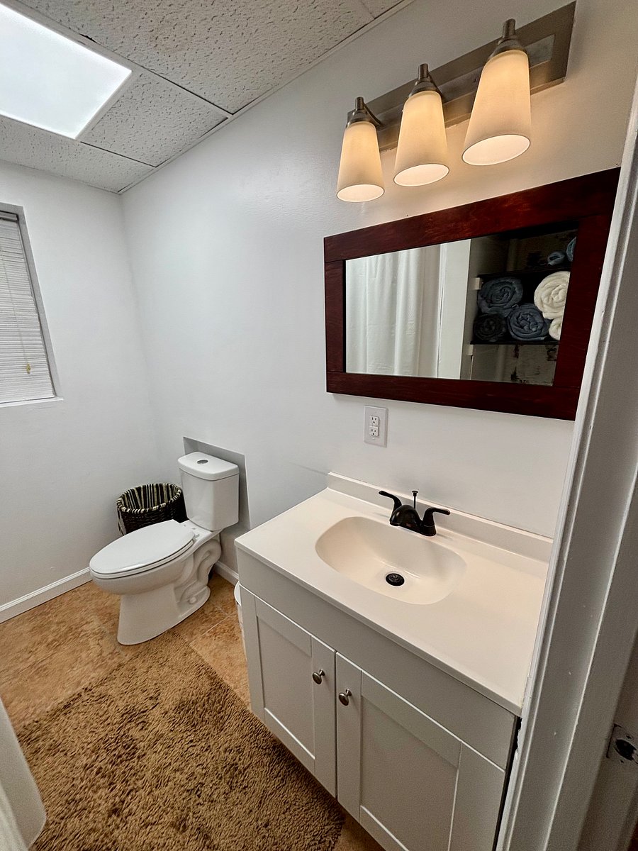 Bathroom stocked with towels, washrags, plunger, toilet cleaner, clothes hamper, and antibacterial hand soap.
