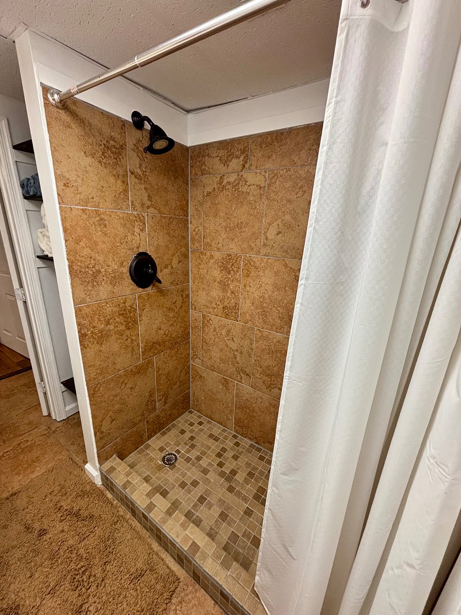 Bathroom stocked with towels, washrags, plunger, toilet cleaner, clothes hamper, and antibacterial hand soap.