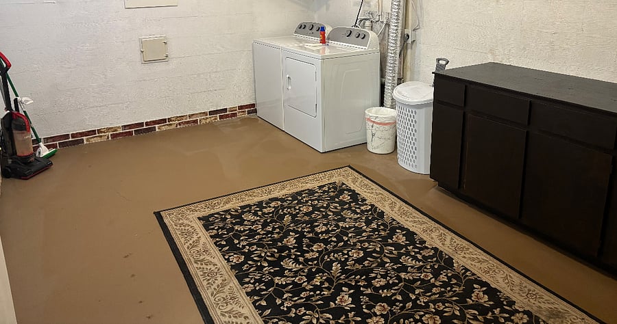 Laundry room with washer/dryer, hamper, trash can, folding area, and cleaning tools (vacuum, mop, broom).