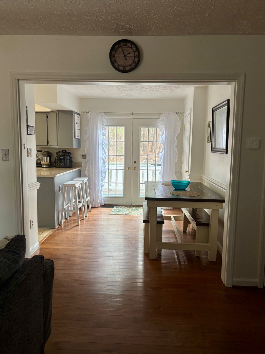 Dining room with farm house table and counter barstools. French doors lead to deck with outdoor dining and lounge seating. Interior door to the right opens to large walk-in pantry,