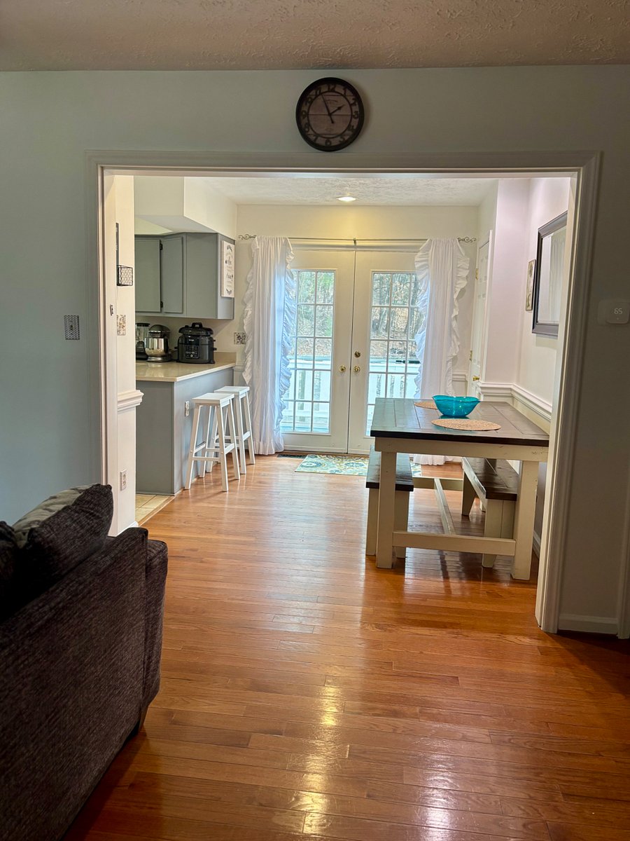 Dining room with farm house table and counter barstools. French doors lead to deck with outdoor dining and lounge seating. Interior door to the right opens to large walk-in pantry,