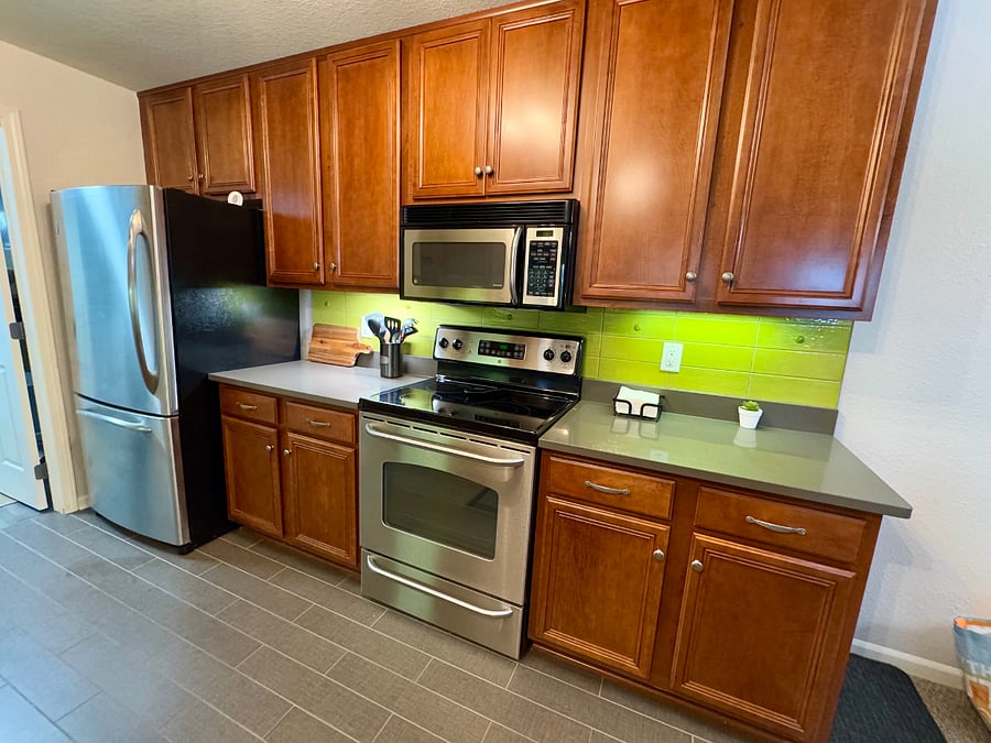 Kitchen features quartz counters, stainless steel appliances and under cabinet lighting.