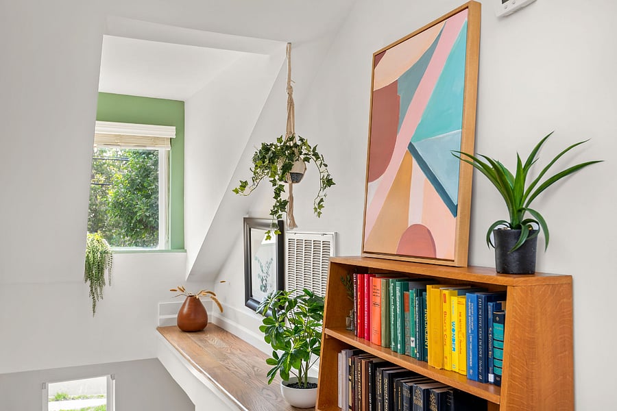 Beautifully decorated stairway with refinished original wood steps and a fully stocked bookshelf